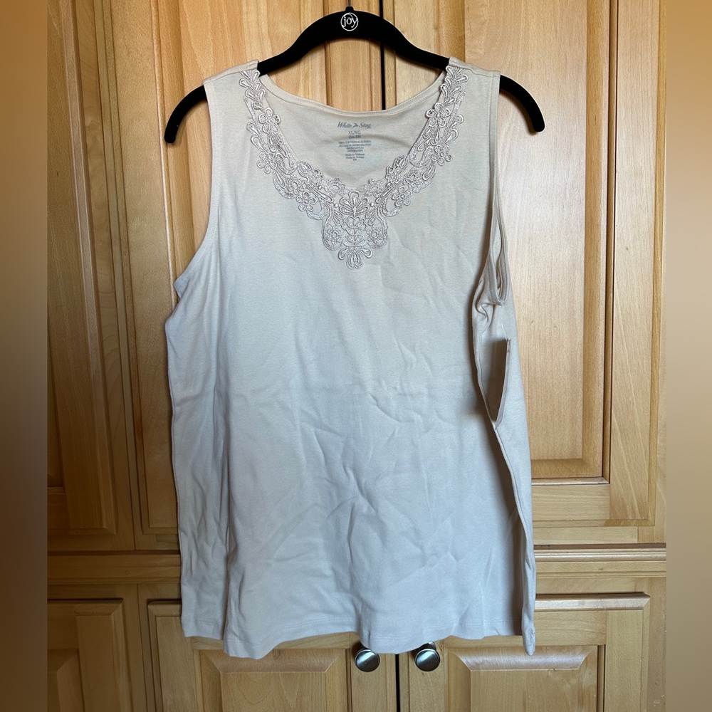 Beige woman’s tank top with details on neck.